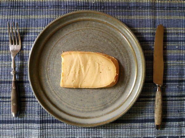 Eine Scheibe Käse auf hellblauem Keramikteller