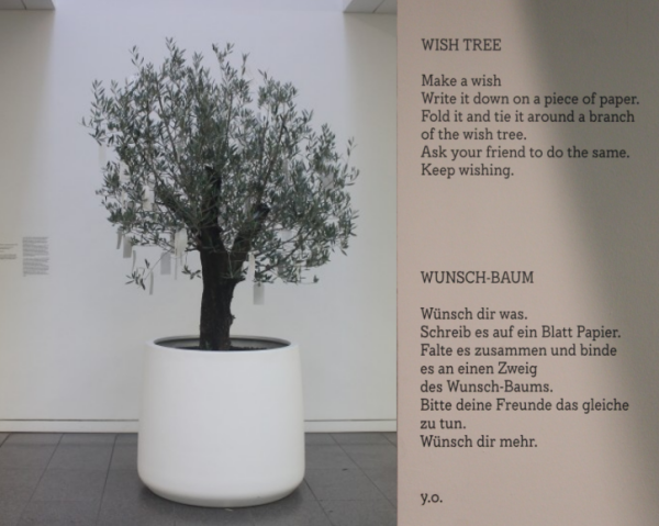 Olivenbaum in weißem Kübel mit weißen Karten für die Wünsche der Besucher*innen