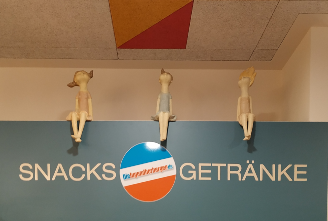 Drei Kinderfiguren sitzen auf dem Snack-Automaten der Jugendherberge