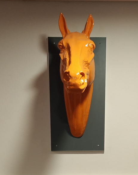 Plastikskulptur eines orangefarbenen Pferdekopfs