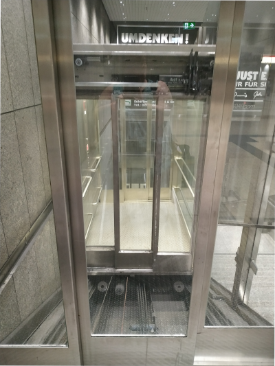 Blick auf einen gläserner Aufzug, der schräg nach oben fährt.