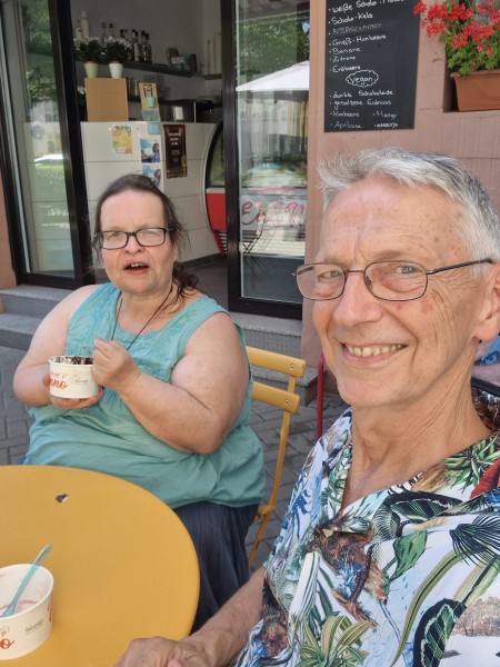 Eisessen in Worms Die Erzählerin Bettina vH mit Uwe an einem gelben Tisch beim Eisessen