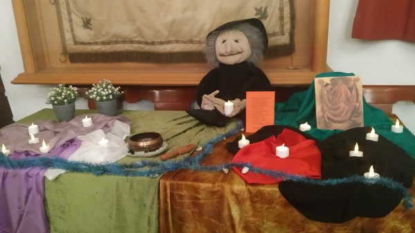 Der Märchentisch zum Hexenabend mit meiner großen Hexenpuppe von Folkmanis, vielen LED-Teelichtern auf grün und goldmelierten Pannésamttüchern