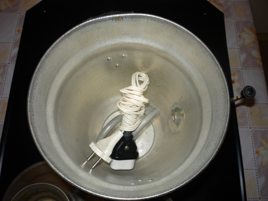 Innenansicht eines metallischen Samowars mit aufgewickeltem weißem Stromkabel und Stecker im Inneren